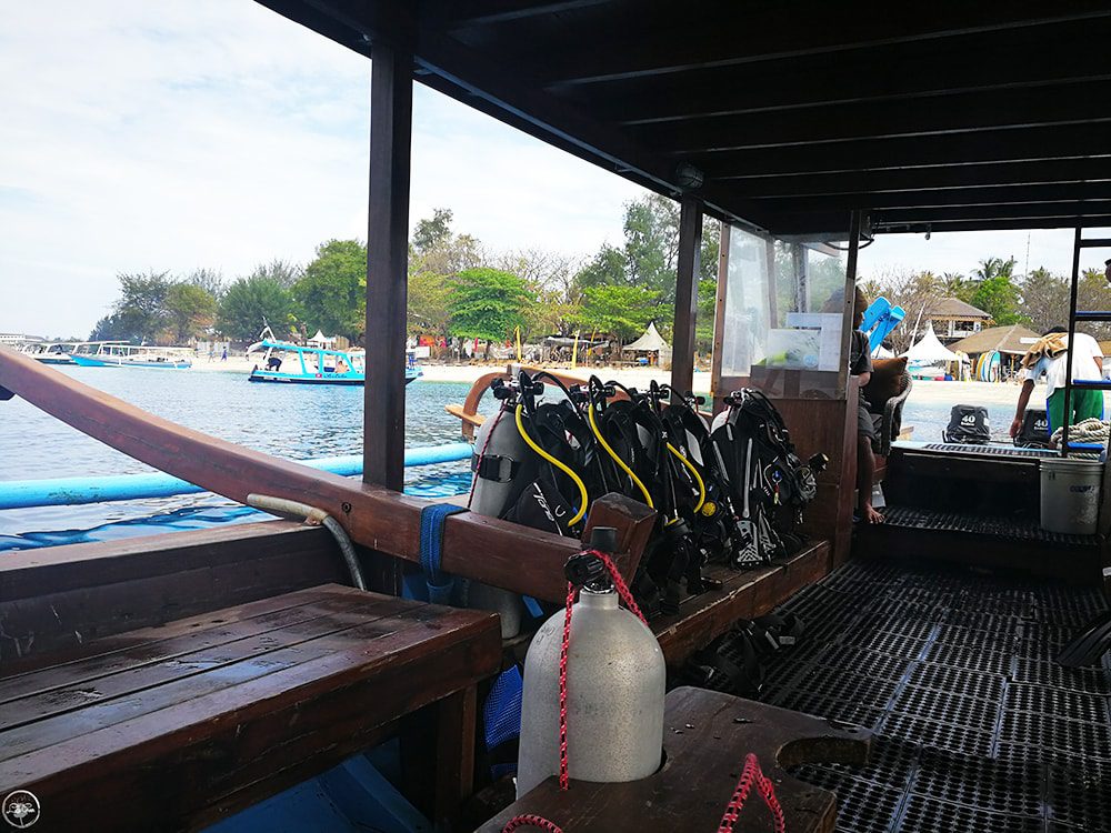 Diving gear on a boat in the Gili Islands, Indonesia with a scenic island background.