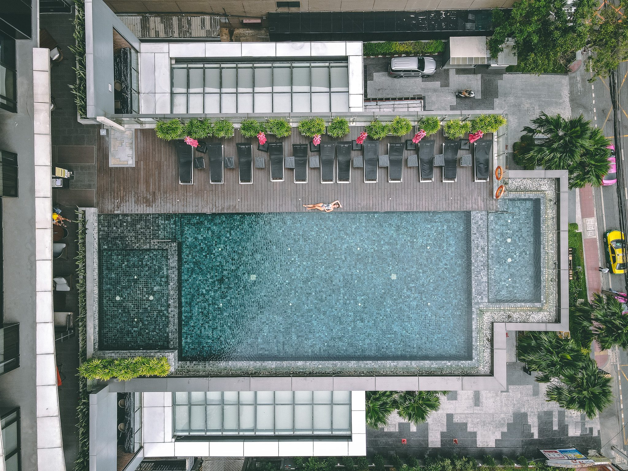 Aerial view of a rooftop pool with loungers in Bangkok, Thailand.
