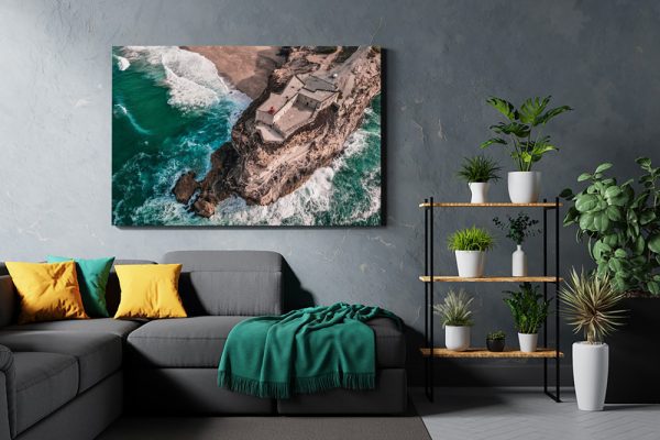 Aerial Nazare cliffs art print in modern living room with gray sofa and plants.