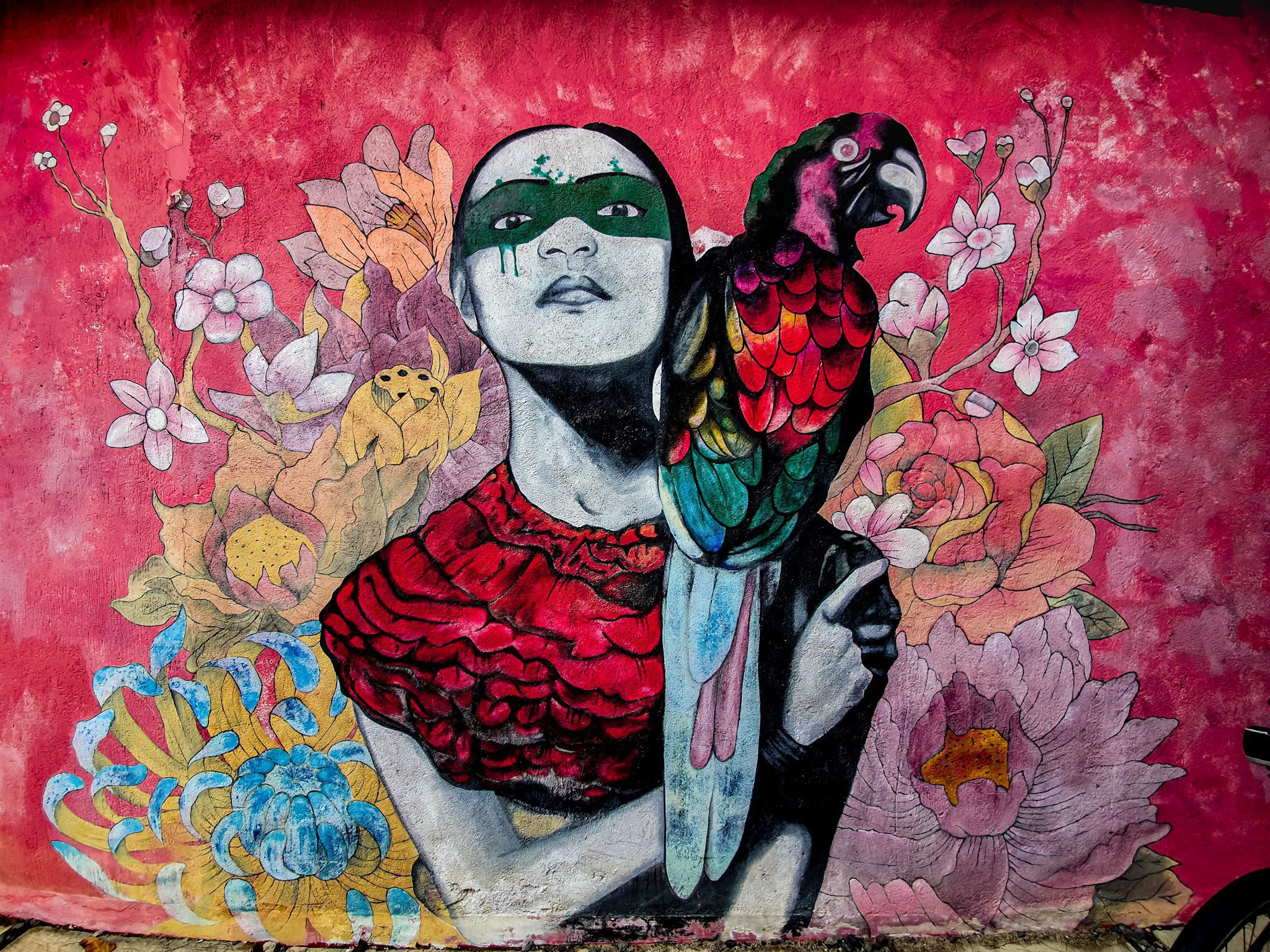 Colorful mural of a person with a parrot on a floral background in the Gili Islands.