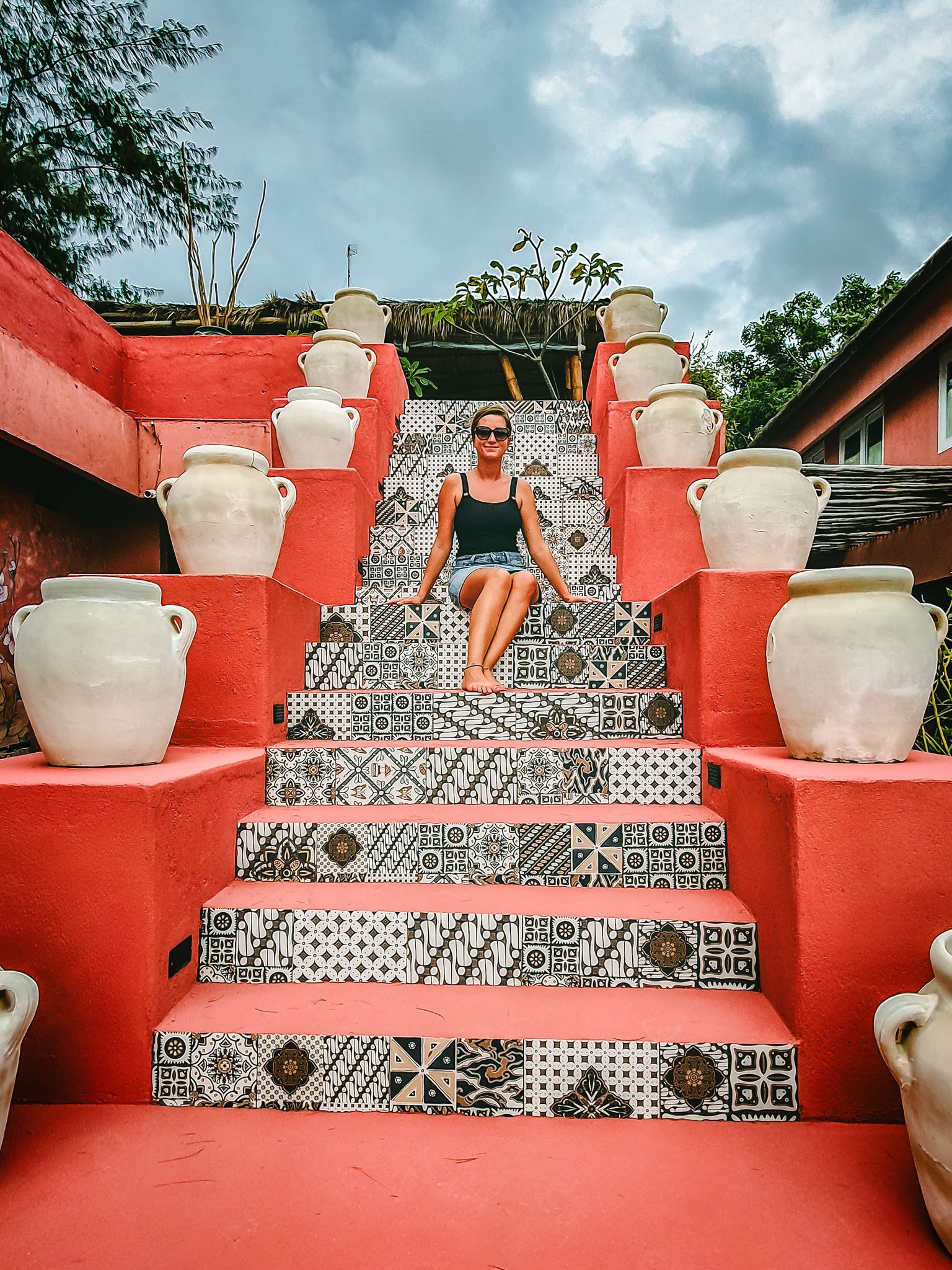 Woman sitting on patterned steps surrounded by pots in the Gili Islands.