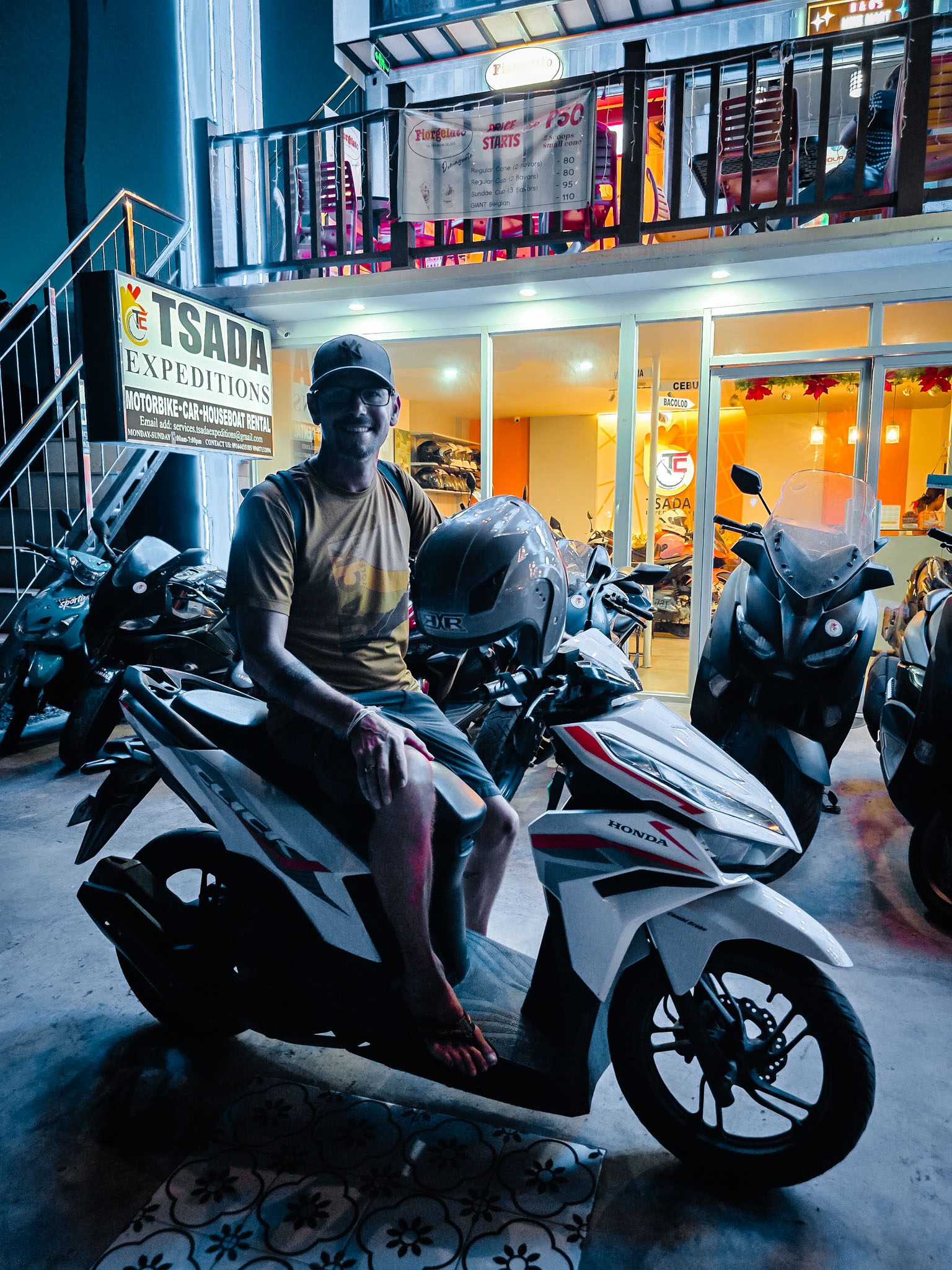 Man seated on a scooter at Tsada Expeditions rental shop in Dumaguete, Philippines.