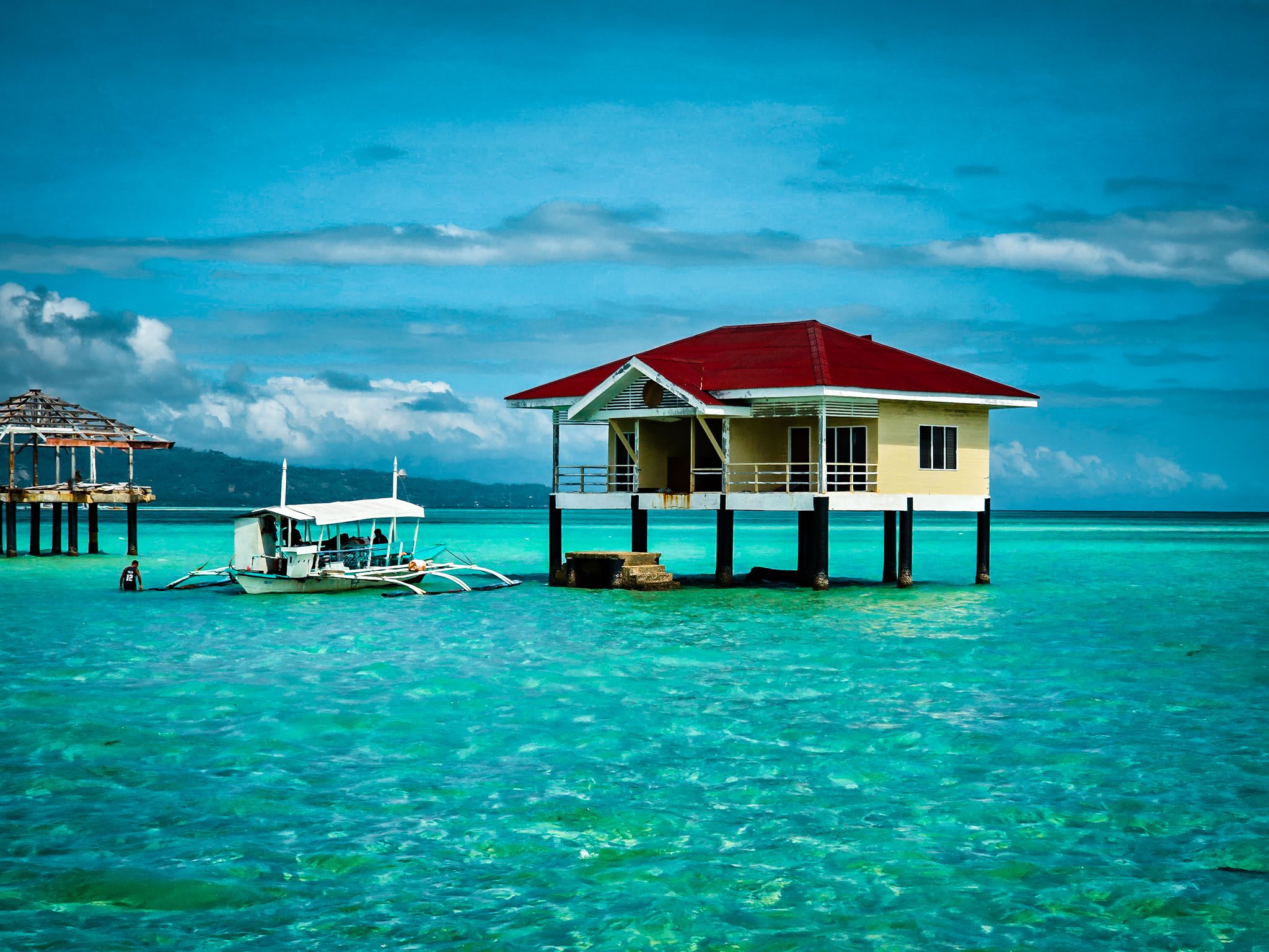 Stilt house and boat on turquoise waters in Dumaguete, Philippines.
