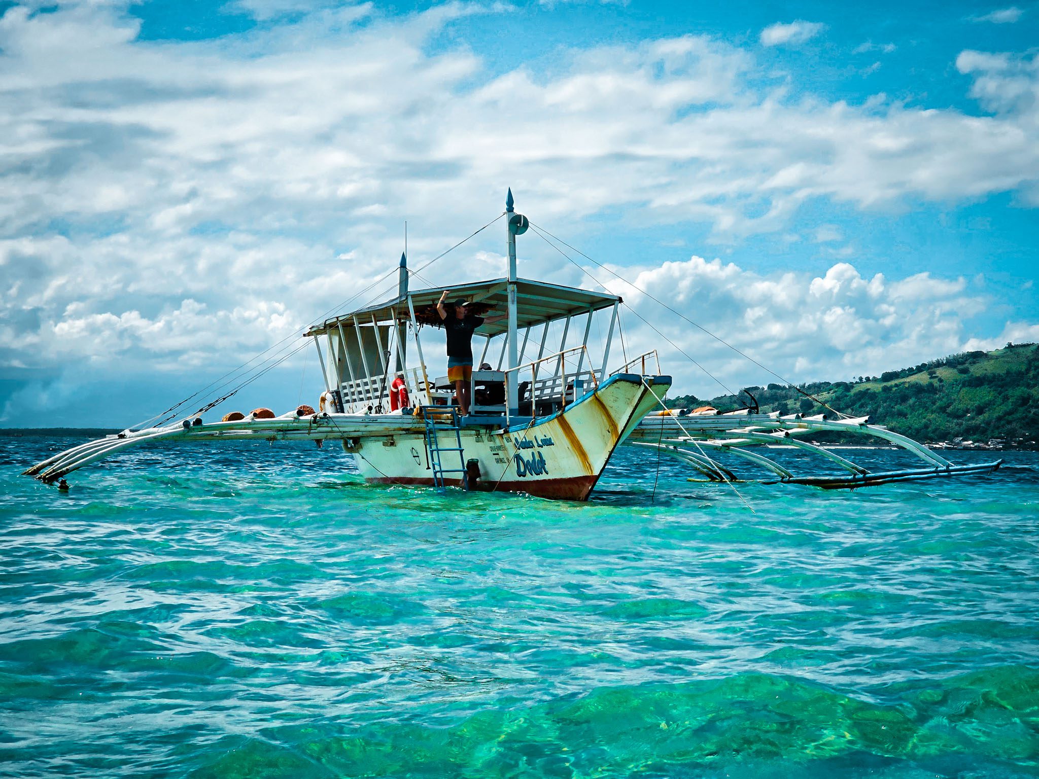 Traditional outrigger boat on clear blue waters near Dumaguete, Philippines.