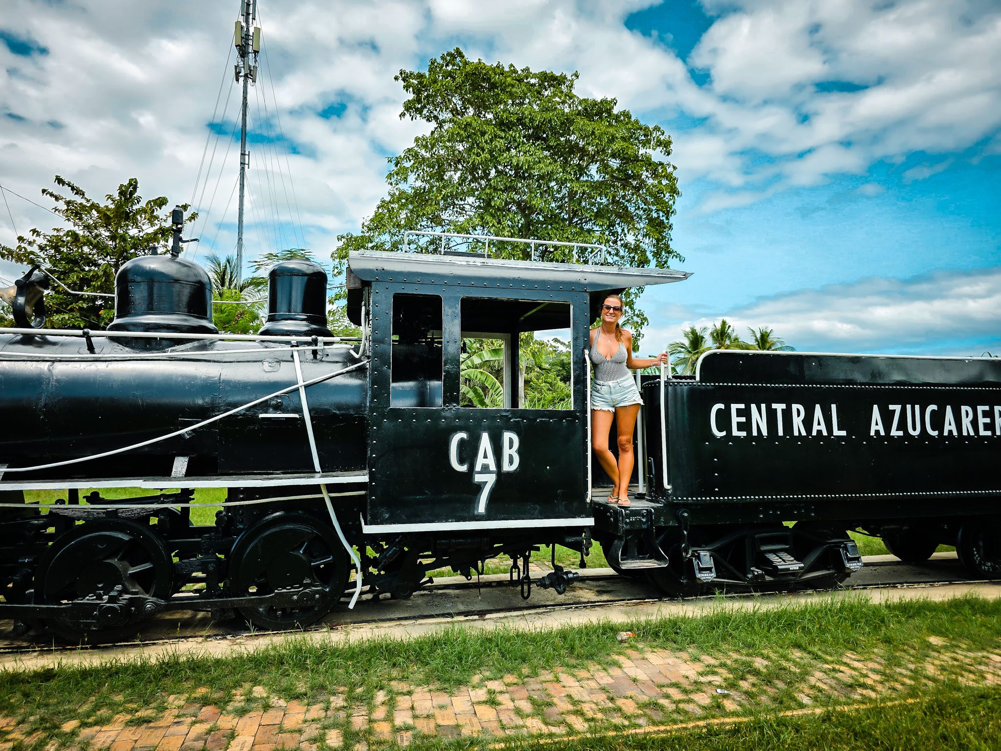 A person stands on a historic train in Dumaguete, Philippines, under a blue sky.