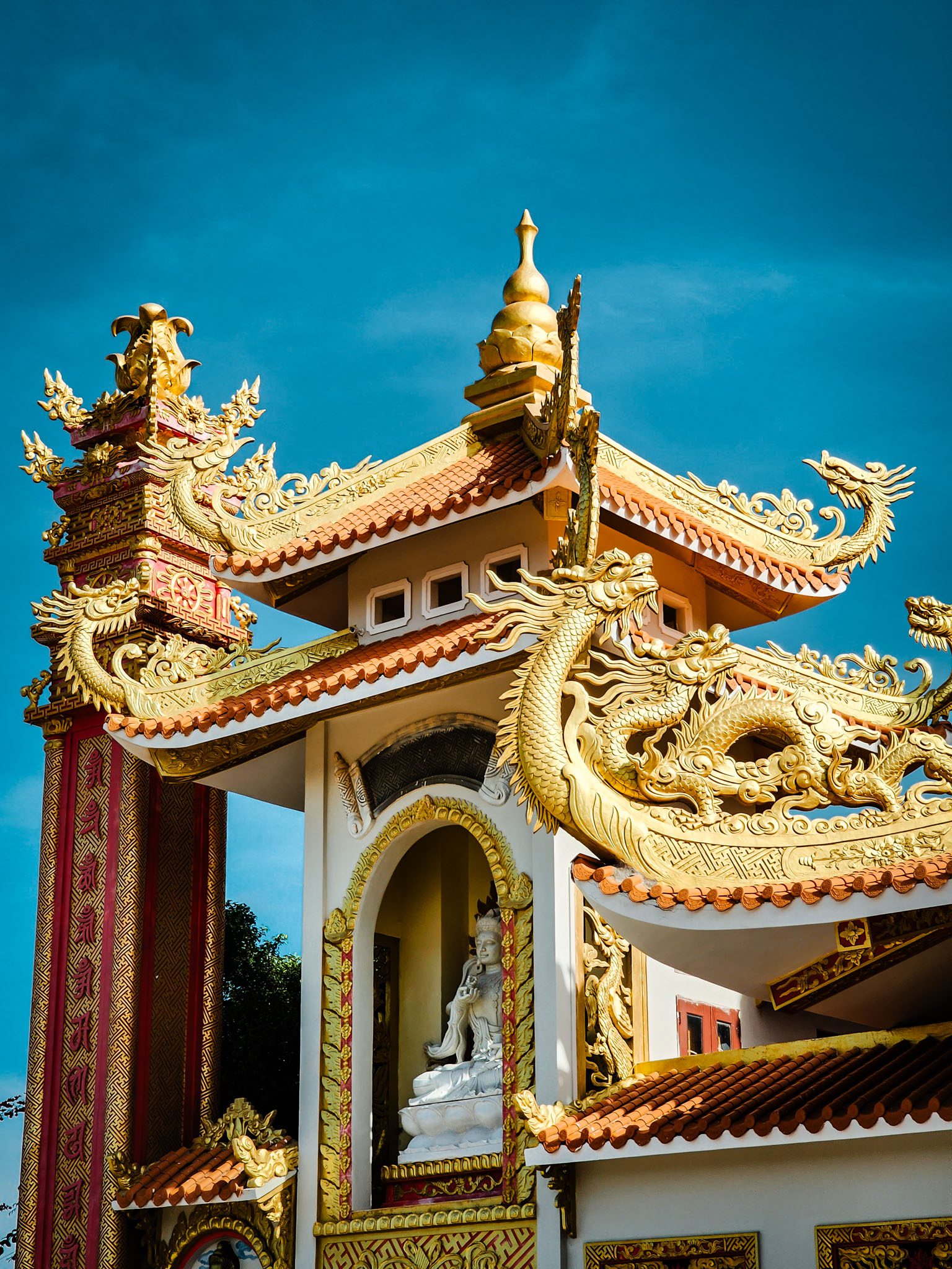 Golden dragon-adorned temple in Mui Ne, Vietnam under a clear blue sky.