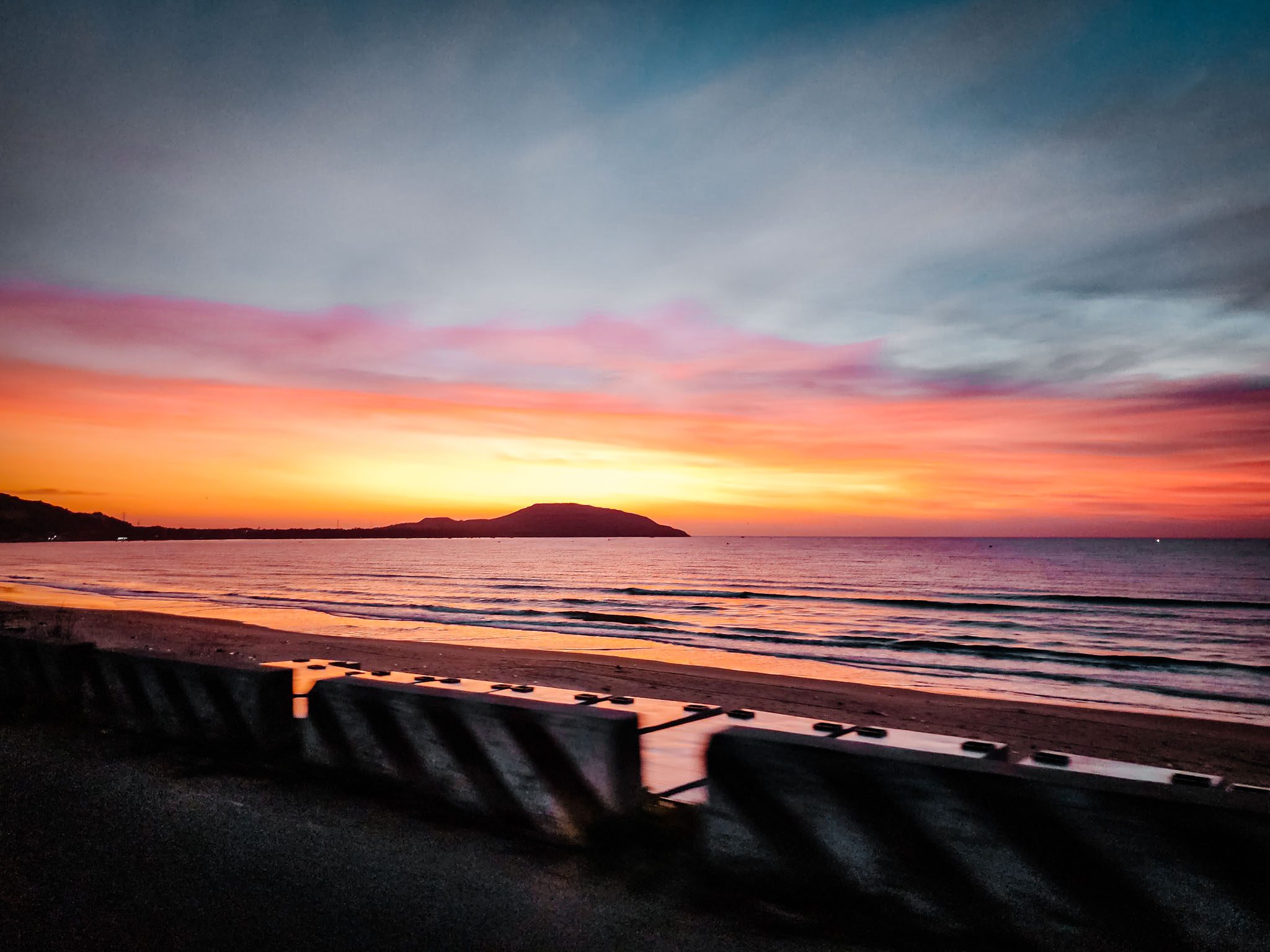 Vibrant sunset over the ocean at Mui Ne, Vietnam, with colorful sky and gentle waves.