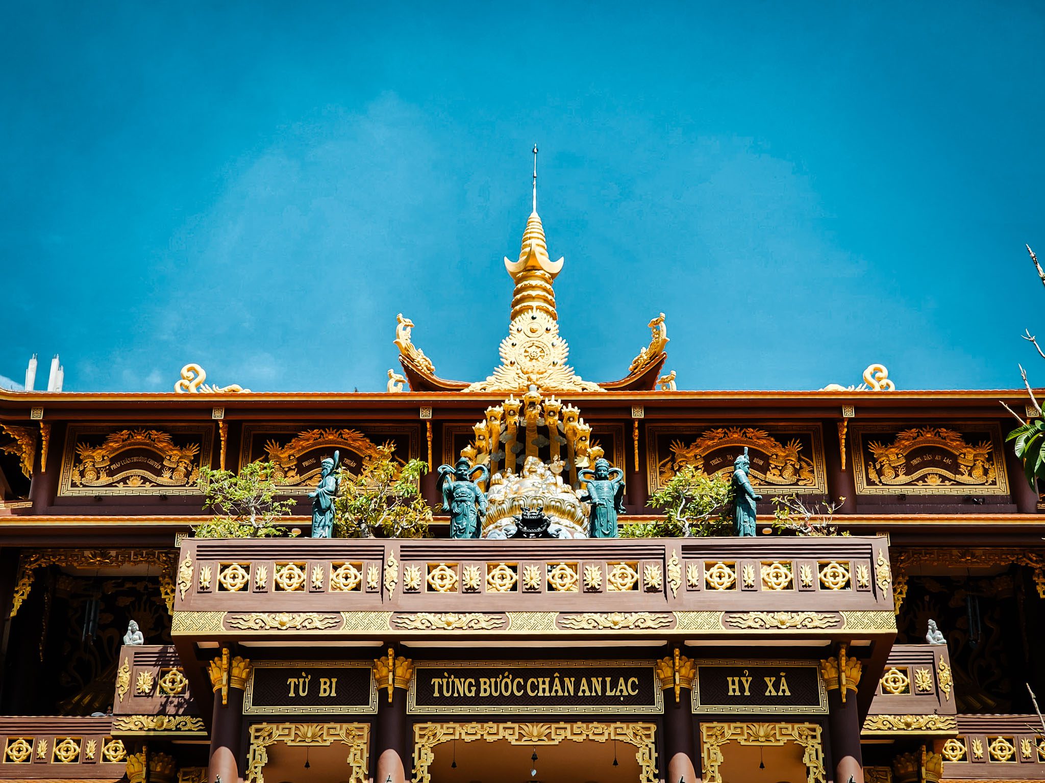 Ornate temple facade with gold accents under blue sky in Mui Ne, Vietnam.