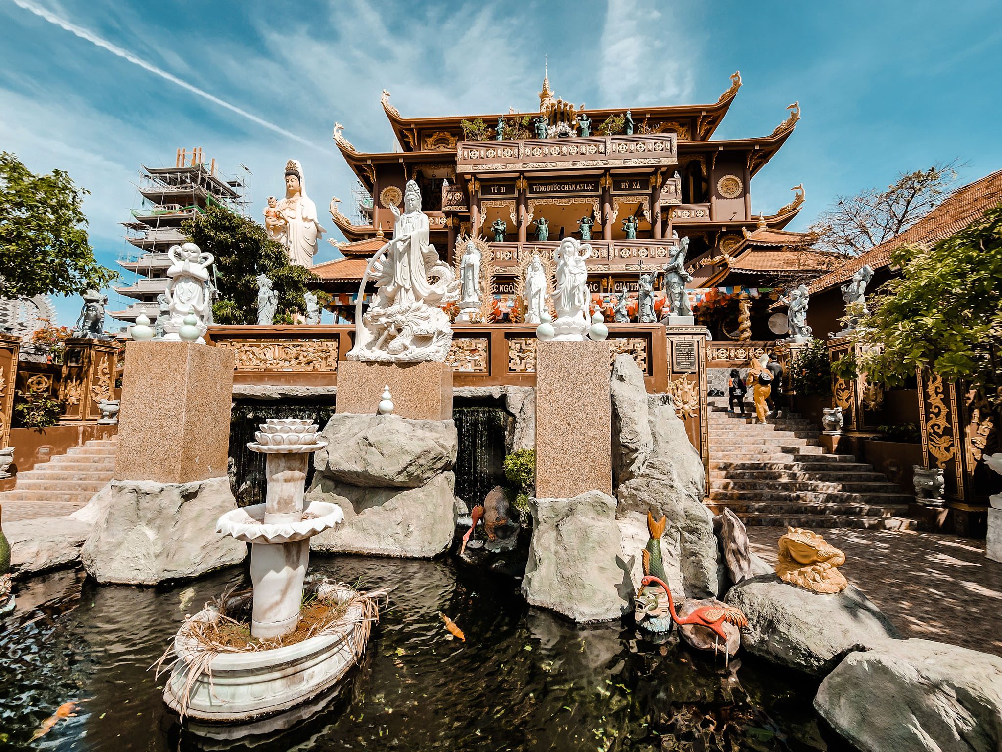 Traditional temple with stone statues and serene pond in Mui Ne, Vietnam.