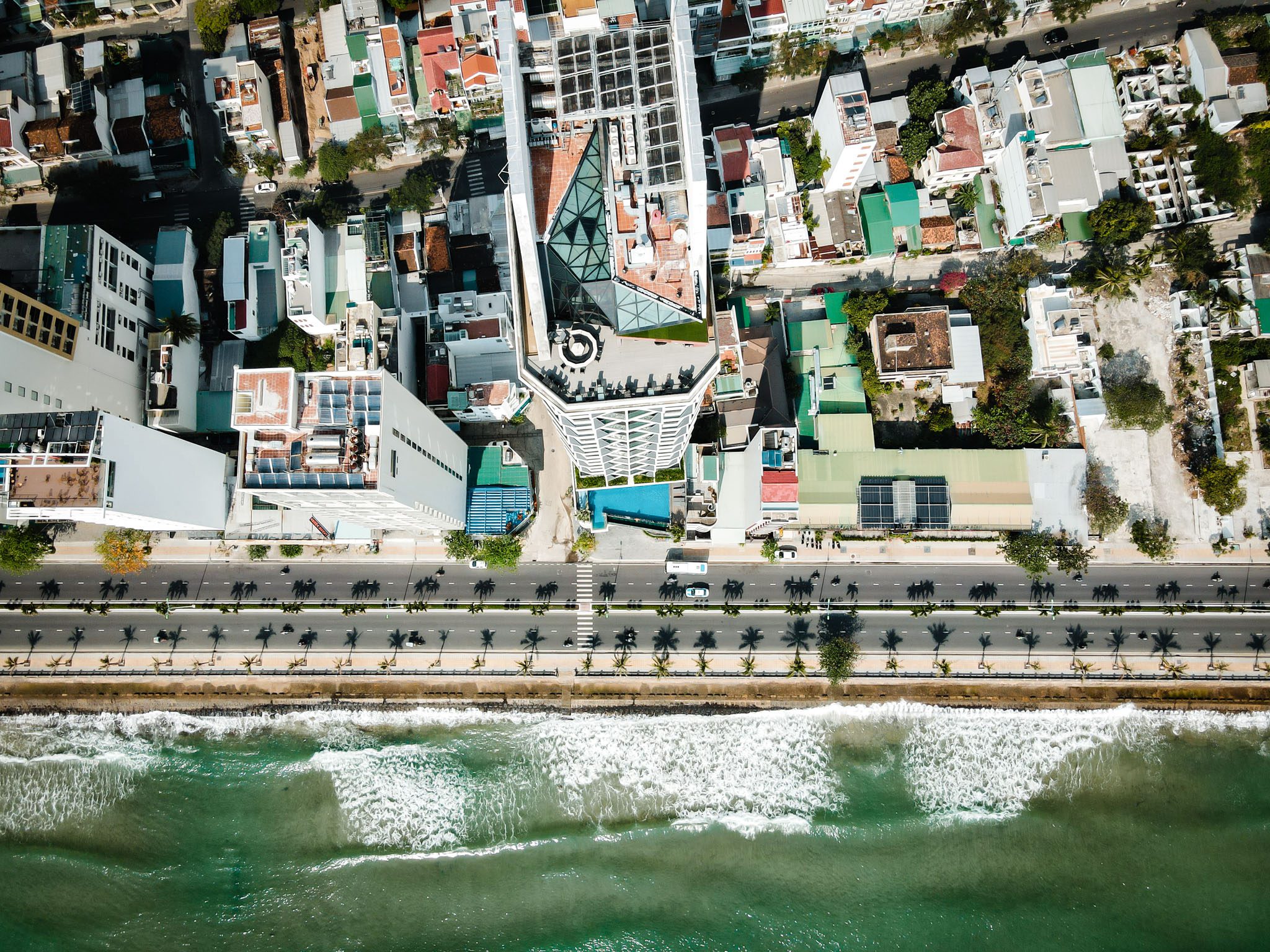 Aerial view of Nha Trang coastline with city streets and ocean waves.