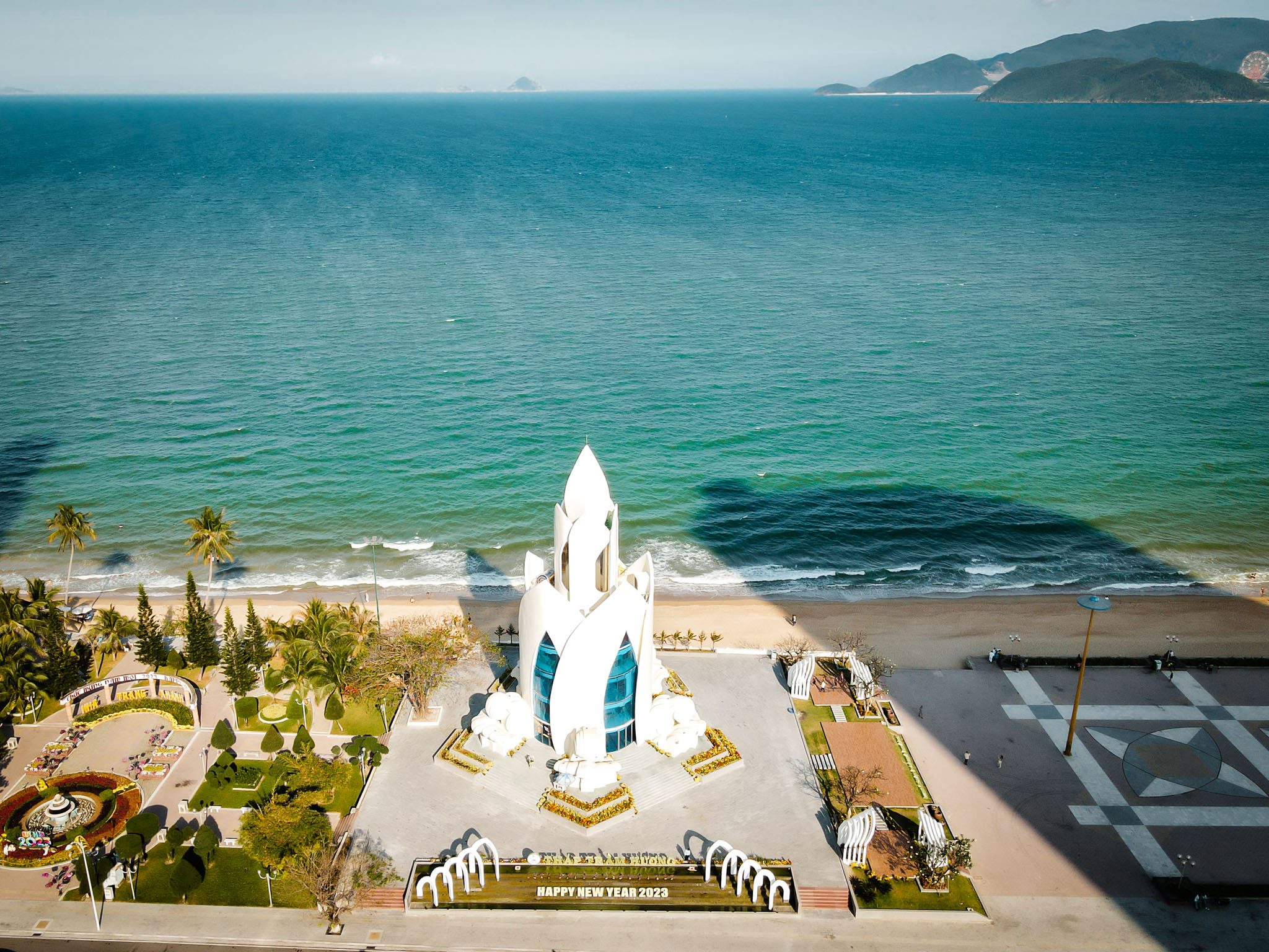 Aerial view of Nha Trang beach and coastal architecture with ocean waves and green landscape.
