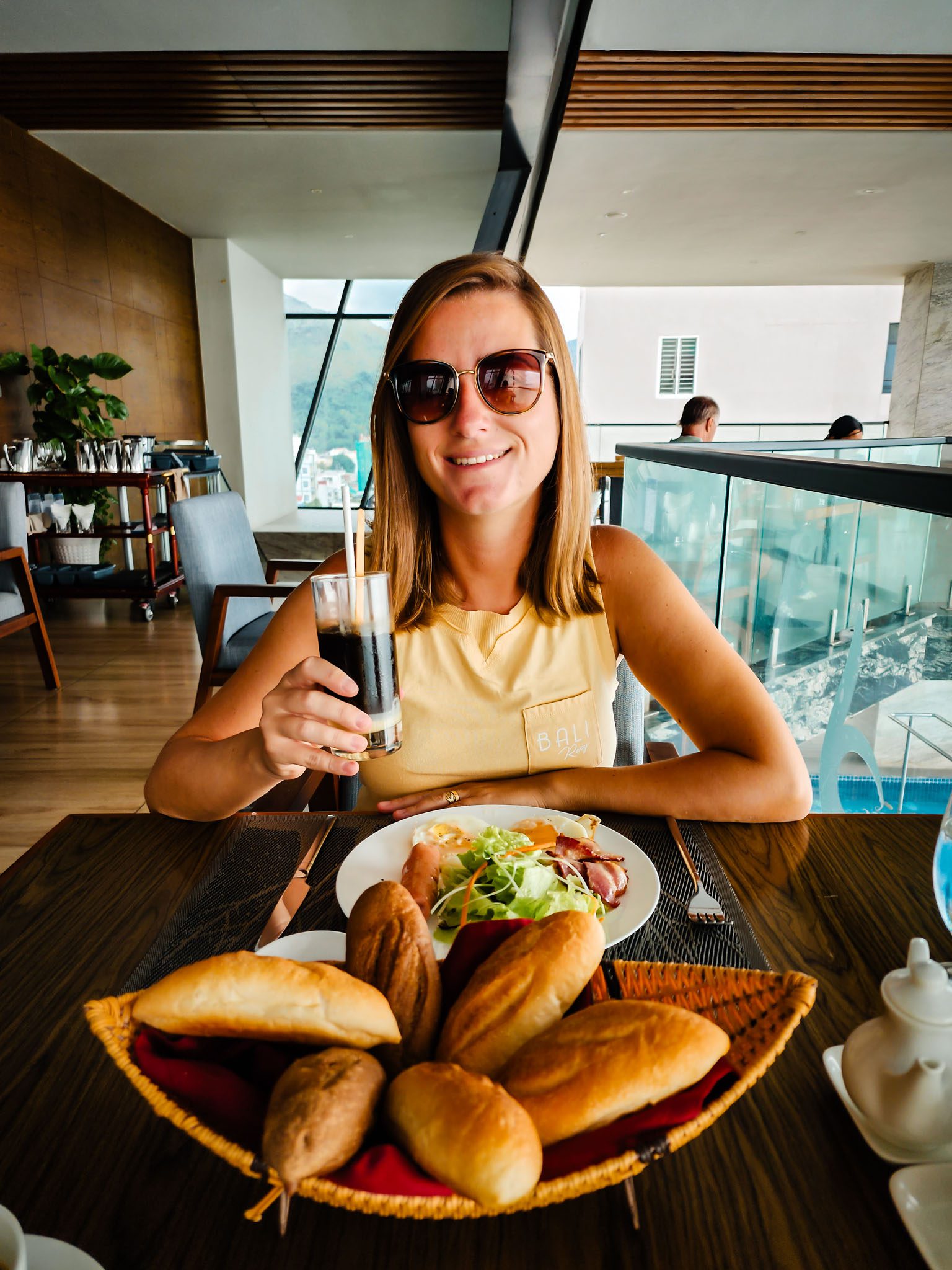 Woman enjoying breakfast with bread and iced coffee in a Nha Trang restaurant.