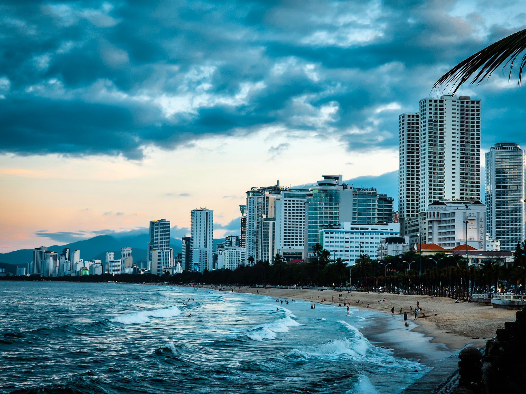 Nha Trang beachfront with high-rise buildings and a vibrant sea at sunset.