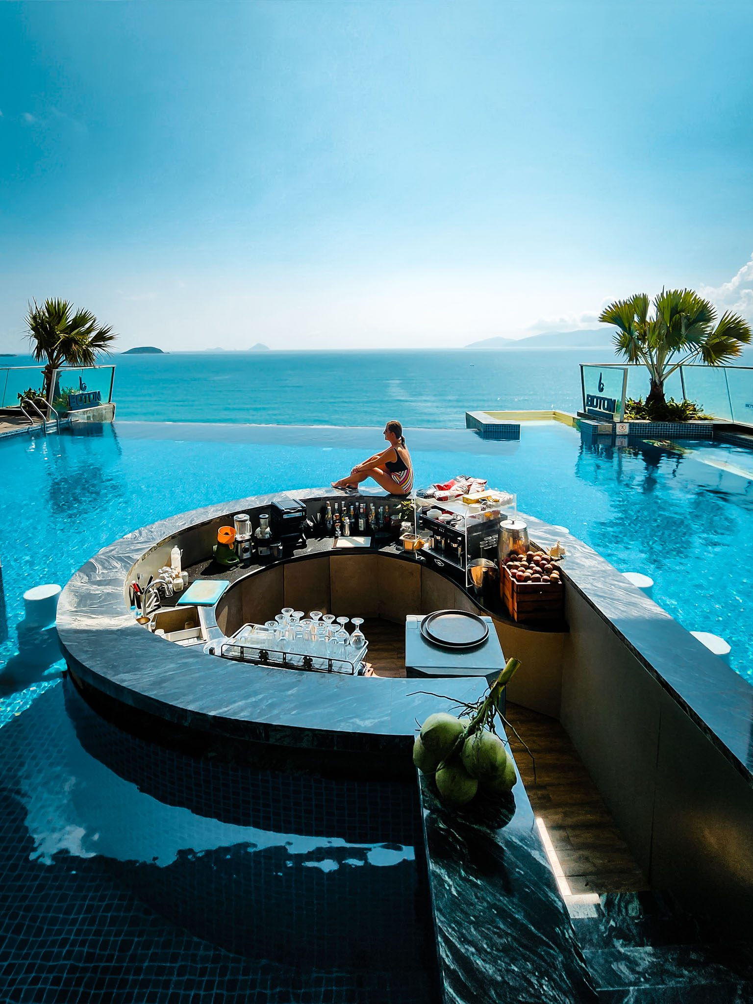 Infinity pool with swim-up bar and ocean view in Nha Trang under a clear blue sky.
