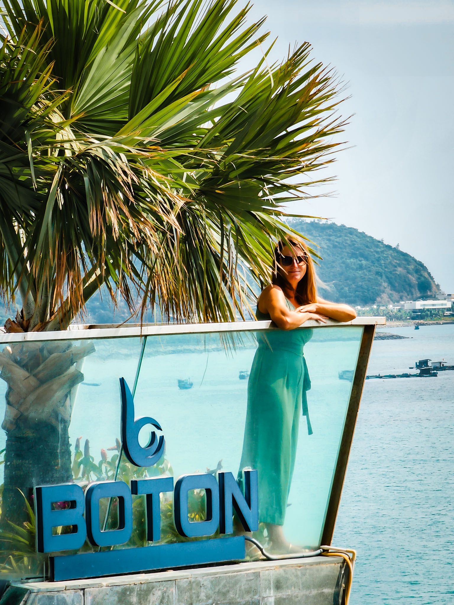 Woman in front of a palm tree at Boton, Nha Trang with ocean view.
