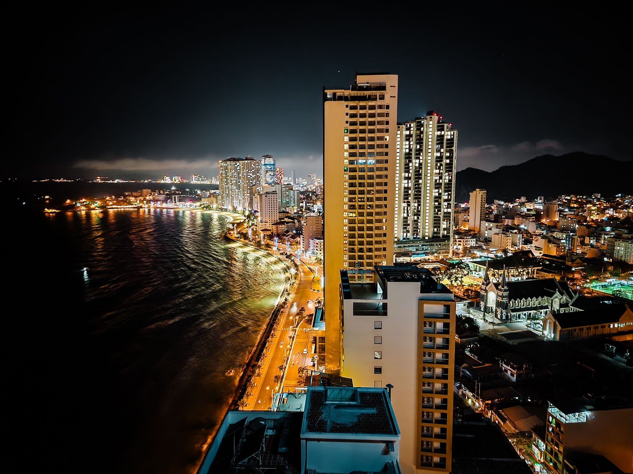 Night skyline of Nha Trang with illuminated buildings along the waterfront.