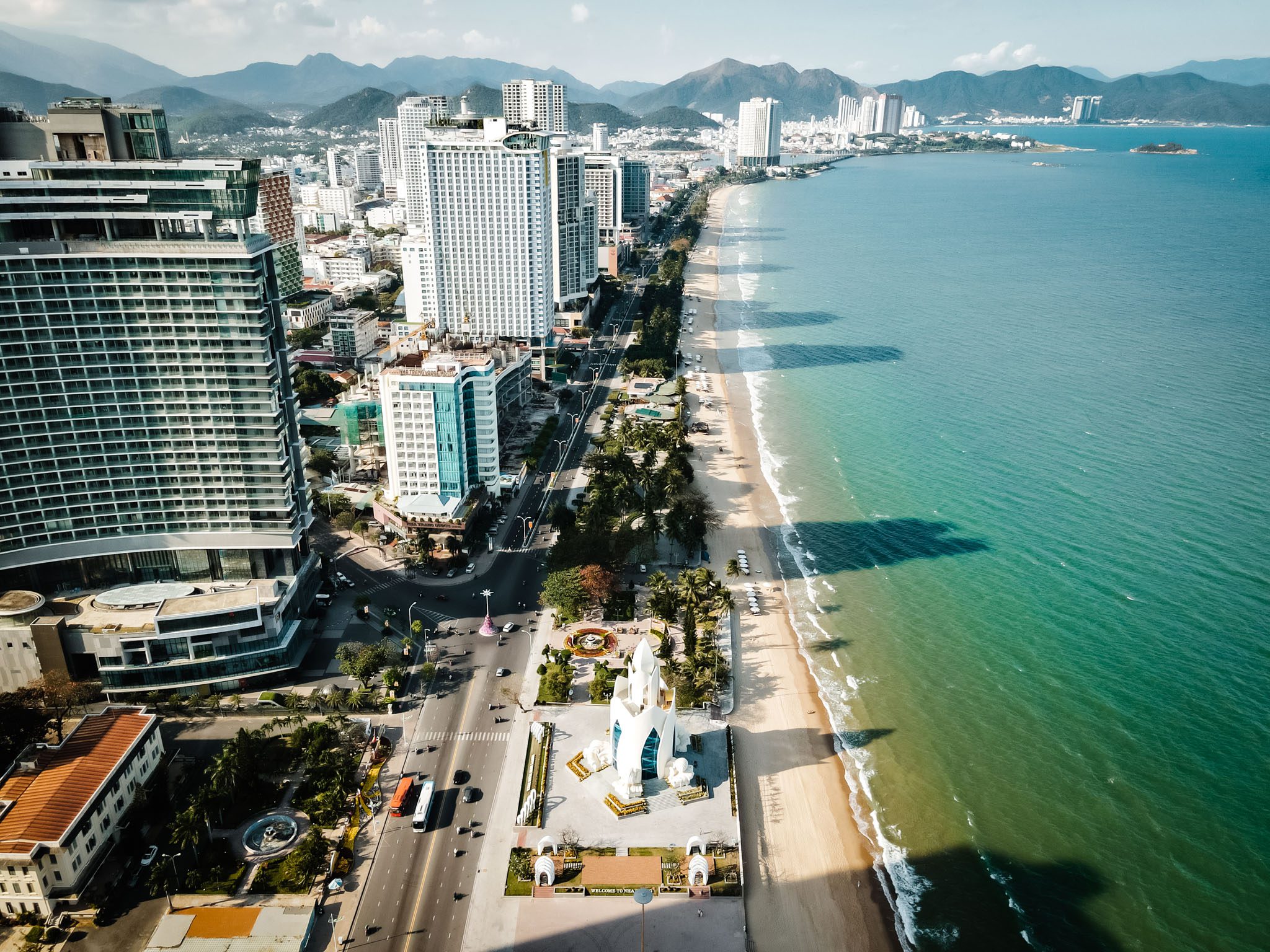 Aerial view of Nha Trang cityscape and sandy beach along the turquoise coastline.