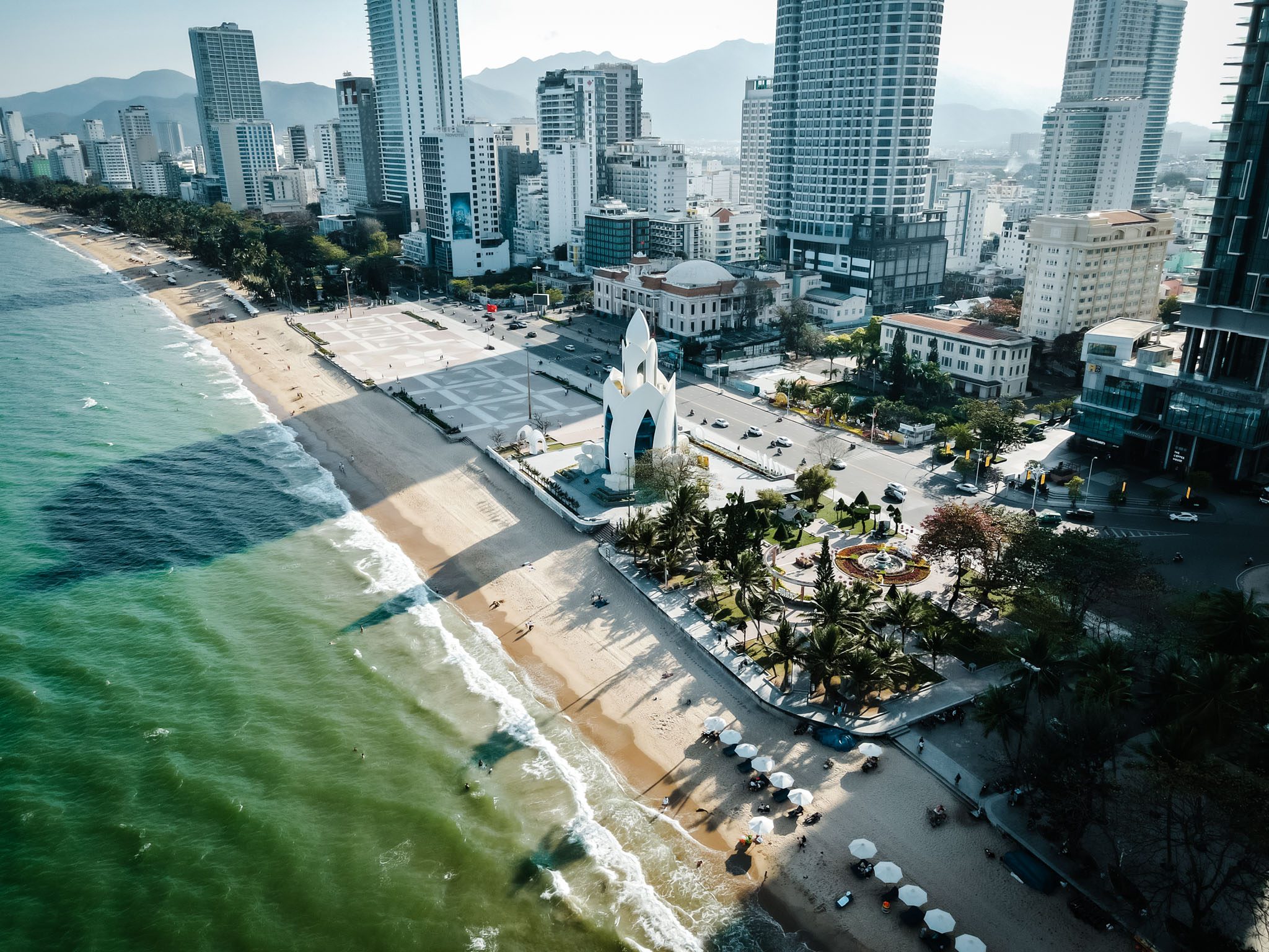 Aerial view of Nha Trang beach with skyscrapers and a landmark building near the shore.